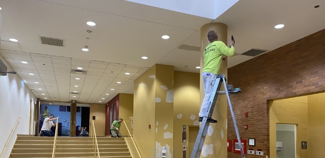 Painter preparing ceiling for interior painting of school facility