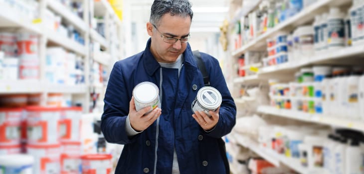 Man choosing the best paint on the shelves of a store